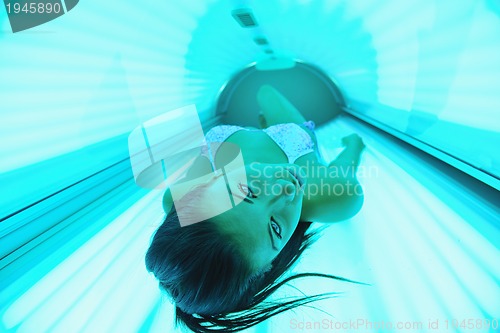 Image of Beautiful young woman tanning in solarium