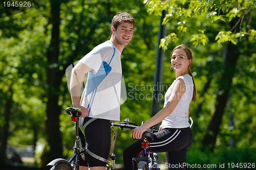 Image of Happy couple riding bicycle outdoors