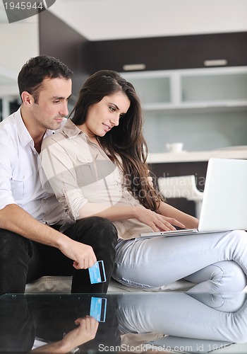 Image of joyful couple relax and work on laptop computer at modern home