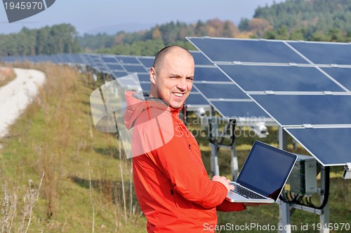 Image of engineer using laptop at solar panels plant field