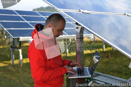 Image of engineer using laptop at solar panels plant field