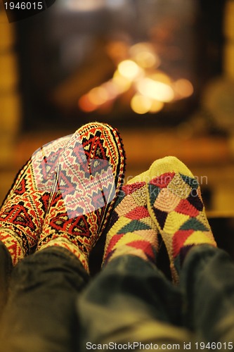 Image of Young romantic couple sitting and relaxing in front of fireplace