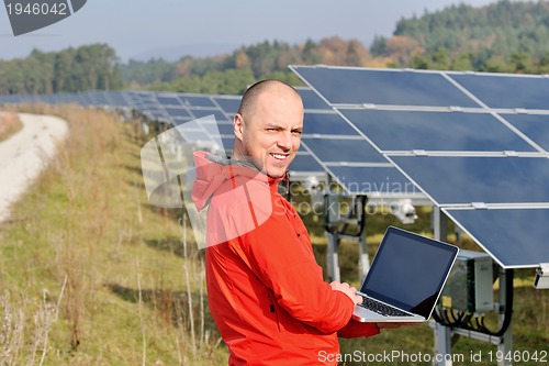 Image of engineer using laptop at solar panels plant field