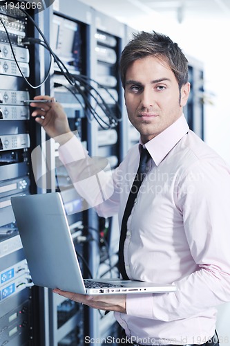 Image of businessman with laptop in network server room