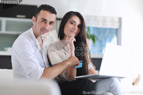 Image of joyful couple relax and work on laptop computer at modern home