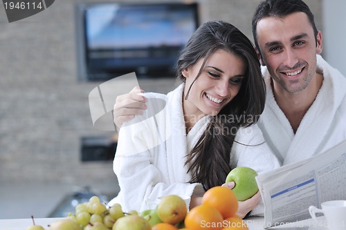 Image of Happy couple reading the newspaper in the kitchen at breakfast