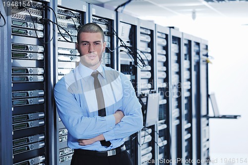 Image of businessman with laptop in network server room