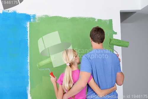 Image of happy couple paint wall at new home