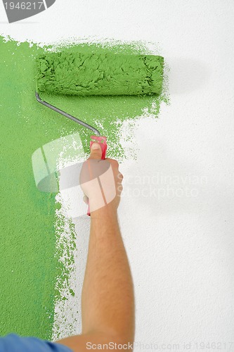 Image of handsome young man paint white wall in color