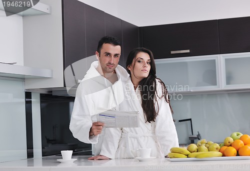 Image of Happy couple reading the newspaper in the kitchen at breakfast