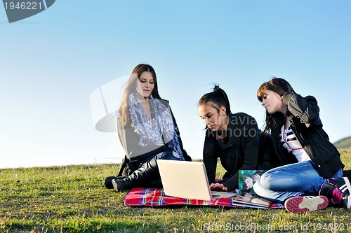 Image of group of teens working on laptop outdoor