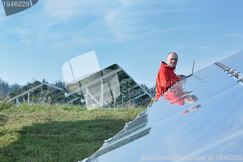 Image of engineer using laptop at solar panels plant field