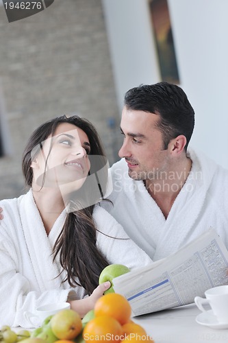Image of Happy couple reading the newspaper in the kitchen at breakfast