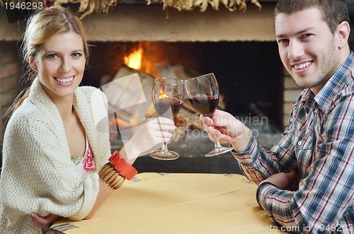 Image of Young romantic couple sitting and relaxing in front of fireplace