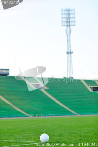 Image of Soccer ball on grass at goal and stadium in background