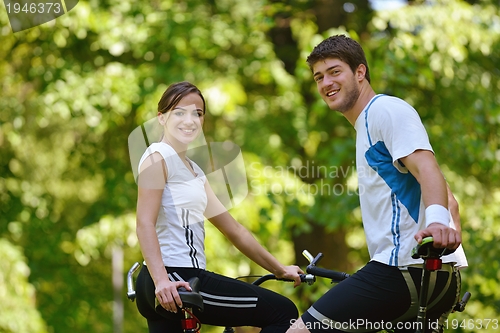 Image of Happy couple riding bicycle outdoors