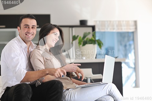 Image of joyful couple relax and work on laptop computer at modern home