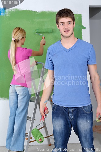 Image of happy couple paint wall at new home