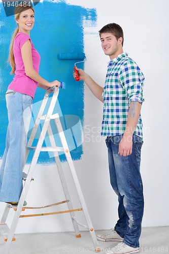 Image of happy couple paint wall at new home