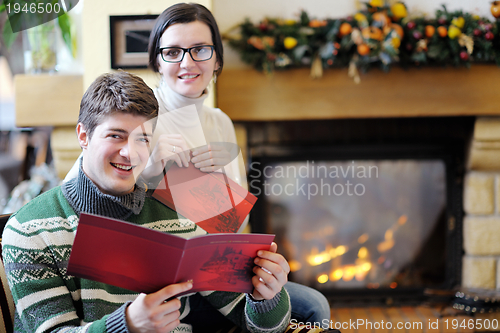 Image of Young romantic couple relax on sofa in front of fireplace at hom