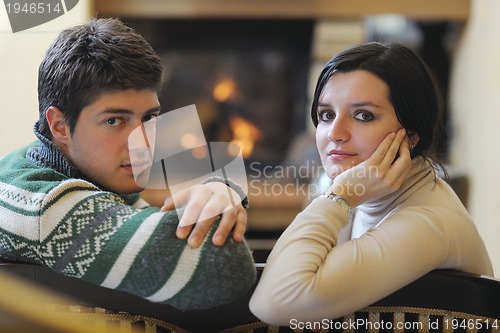 Image of Young romantic couple sitting and relaxing in front of fireplace