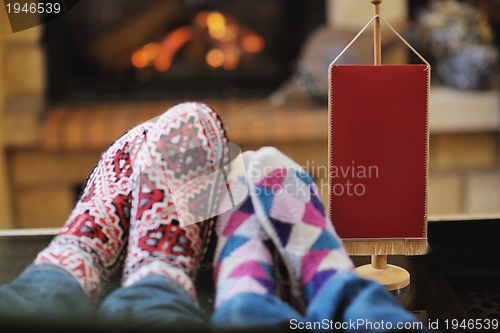 Image of Young romantic couple sitting and relaxing in front of fireplace