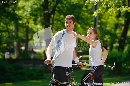 Image of Happy couple riding bicycle outdoors
