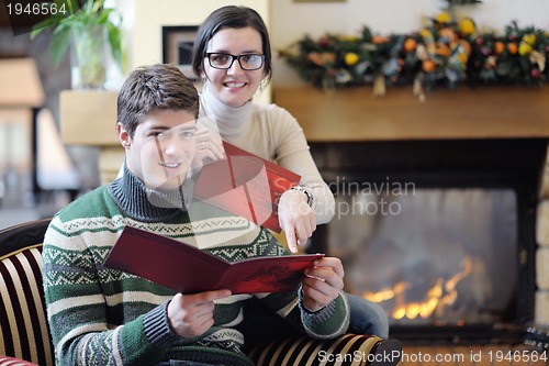 Image of Young romantic couple sitting and relaxing in front of fireplace