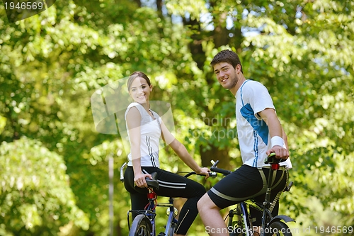 Image of Happy couple riding bicycle outdoors