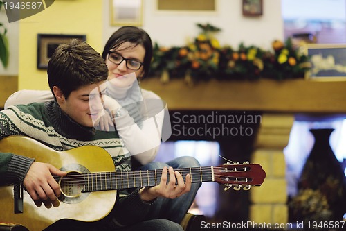 Image of Young romantic couple sitting and relaxing in front of fireplace