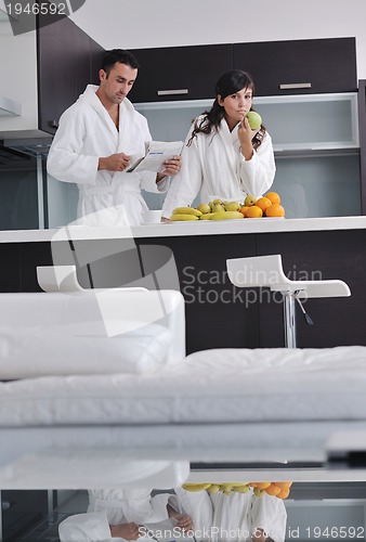 Image of Happy couple reading the newspaper in the kitchen at breakfast