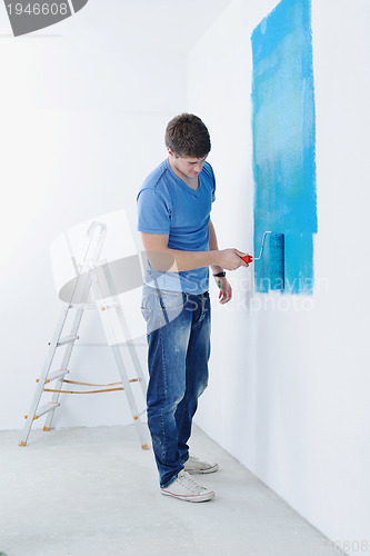 Image of handsome young man paint white wall in color