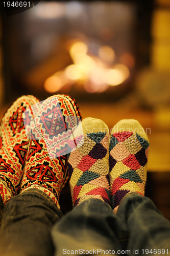 Image of Young romantic couple sitting and relaxing in front of fireplace