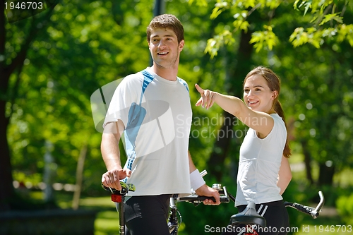 Image of Happy couple riding bicycle outdoors
