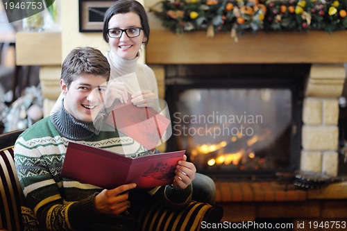 Image of Young romantic couple sitting and relaxing in front of fireplace