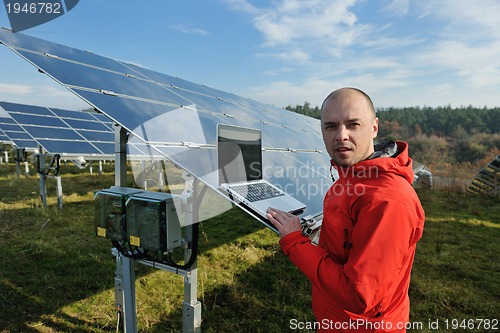 Image of engineer using laptop at solar panels plant field