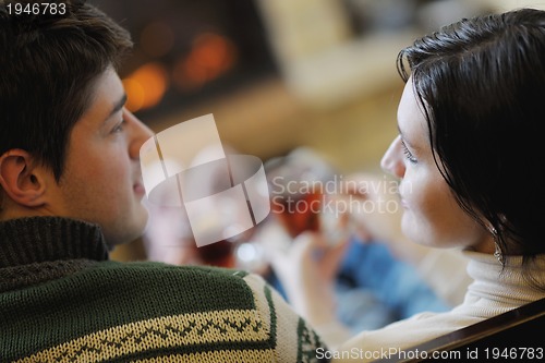 Image of Young romantic couple sitting and relaxing in front of fireplace