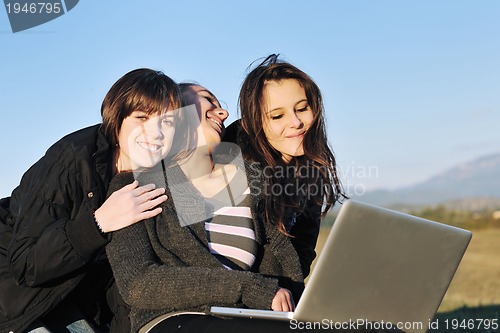 Image of group of teens working on laptop outdoor