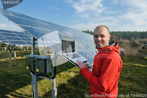 Image of engineer using laptop at solar panels plant field