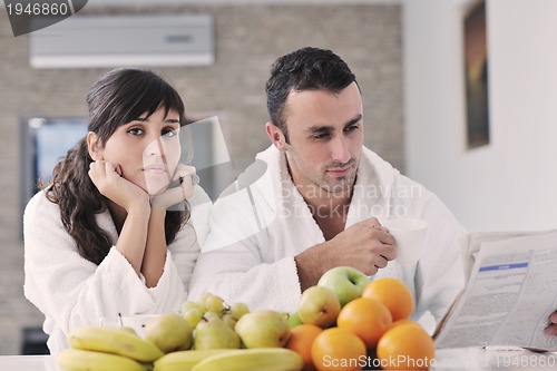 Image of Happy couple reading the newspaper in the kitchen at breakfast