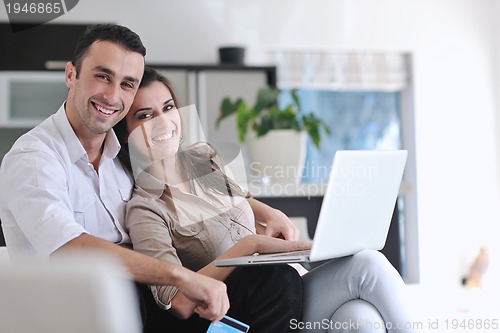 Image of joyful couple relax and work on laptop computer at modern home