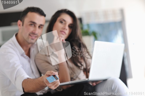 Image of joyful couple relax and work on laptop computer at modern home