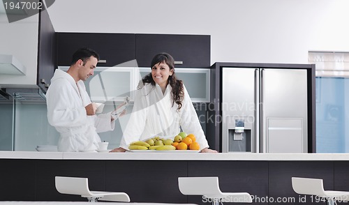 Image of Happy couple reading the newspaper in the kitchen at breakfast