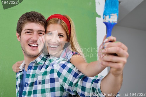 Image of happy couple paint wall at new home