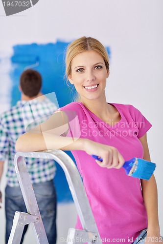 Image of happy couple paint wall at new home