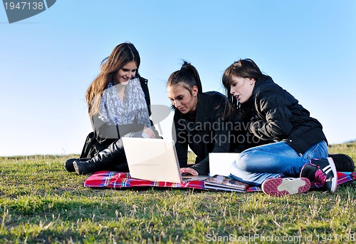 Image of group of teens working on laptop outdoor