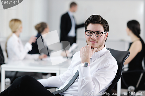 Image of Portrait of a handsome young business man with colleagues in bac