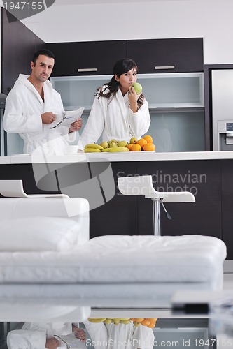Image of Happy couple reading the newspaper in the kitchen at breakfast