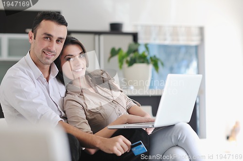 Image of joyful couple relax and work on laptop computer at modern home