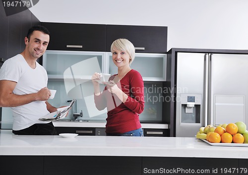 Image of Happy couple reading the newspaper in the kitchen at breakfast